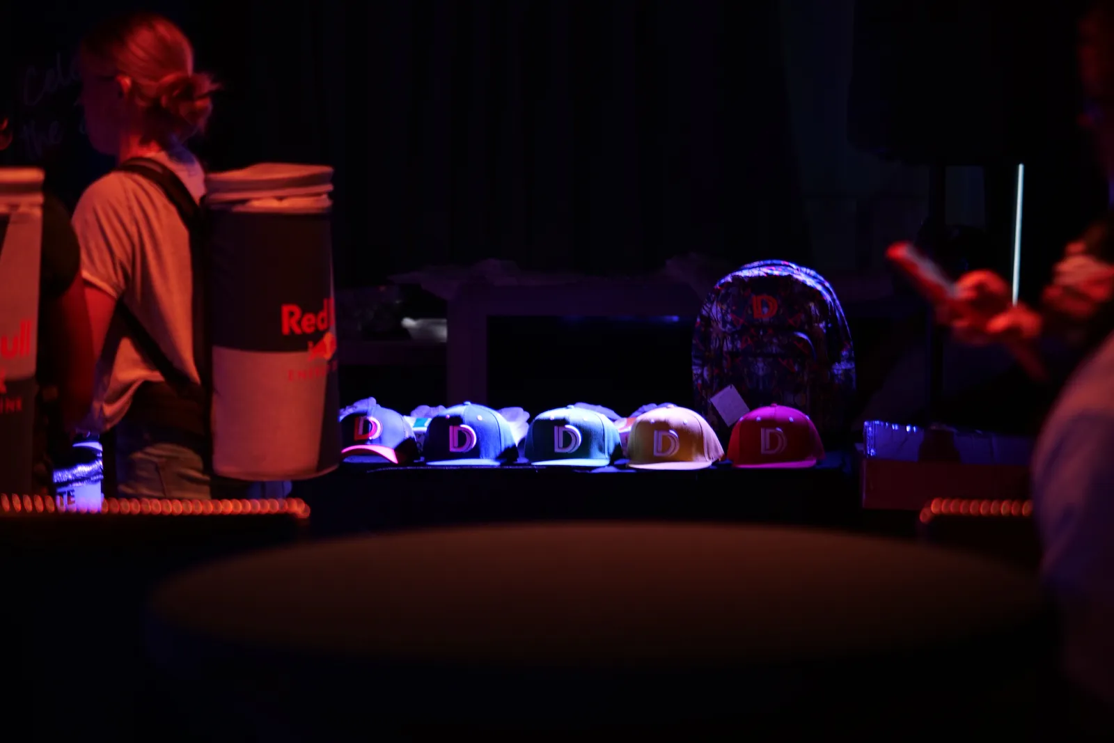 A vendor popup inside Elegance at Event Masterz displays a row of branded snapback hats under moody event lighting, one of many activations the South End Charlotte venue hosts in a single night.